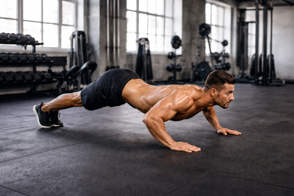 Athlete-performing-hindu-push-up-flow-bodyweight-training-on-gym-floor