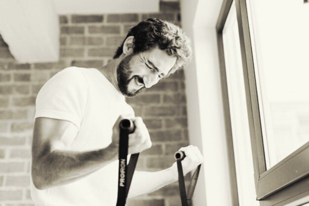 Man-using-resistance-band-for-arm-exercise-in-home-workout