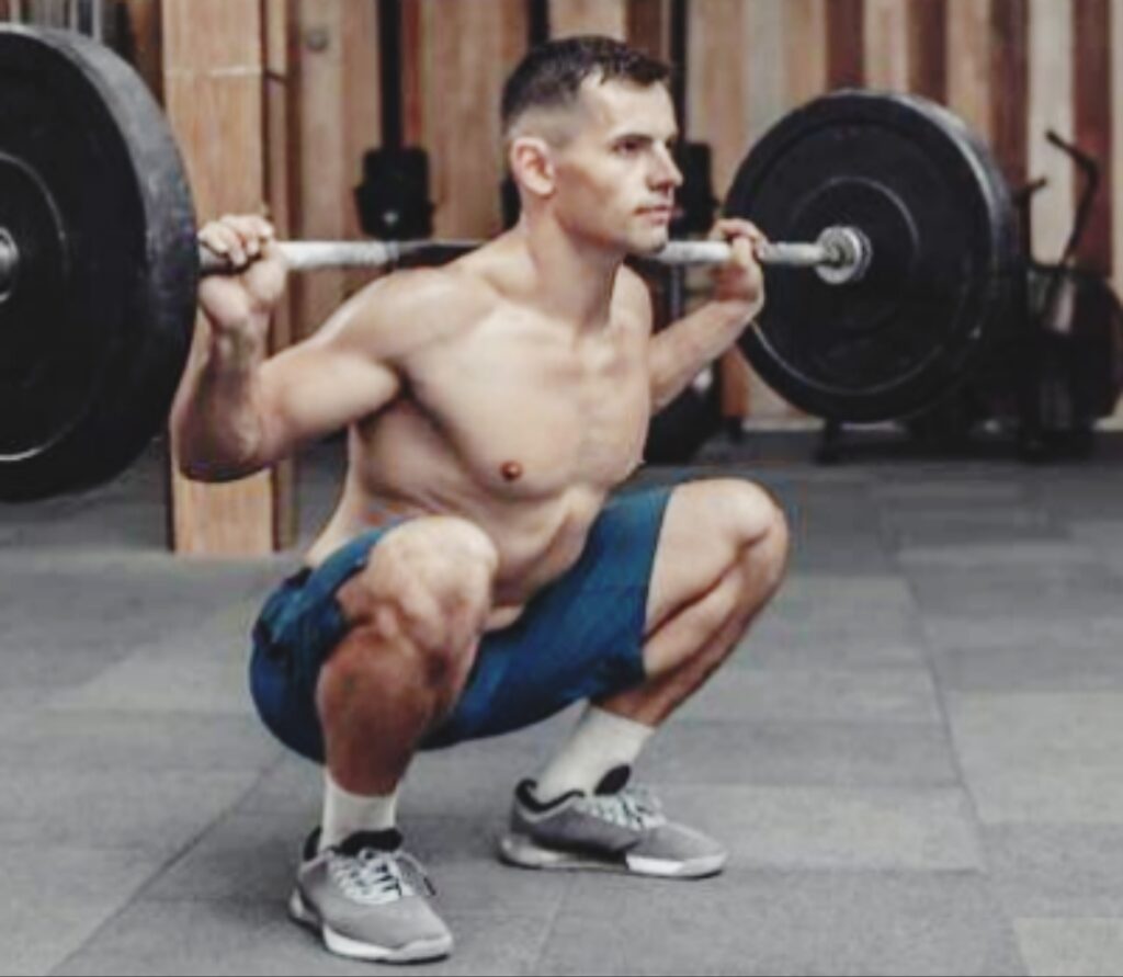 Shirtless-man-performing-a-deep-back-squat-with-a-barbell-in-a-gym
