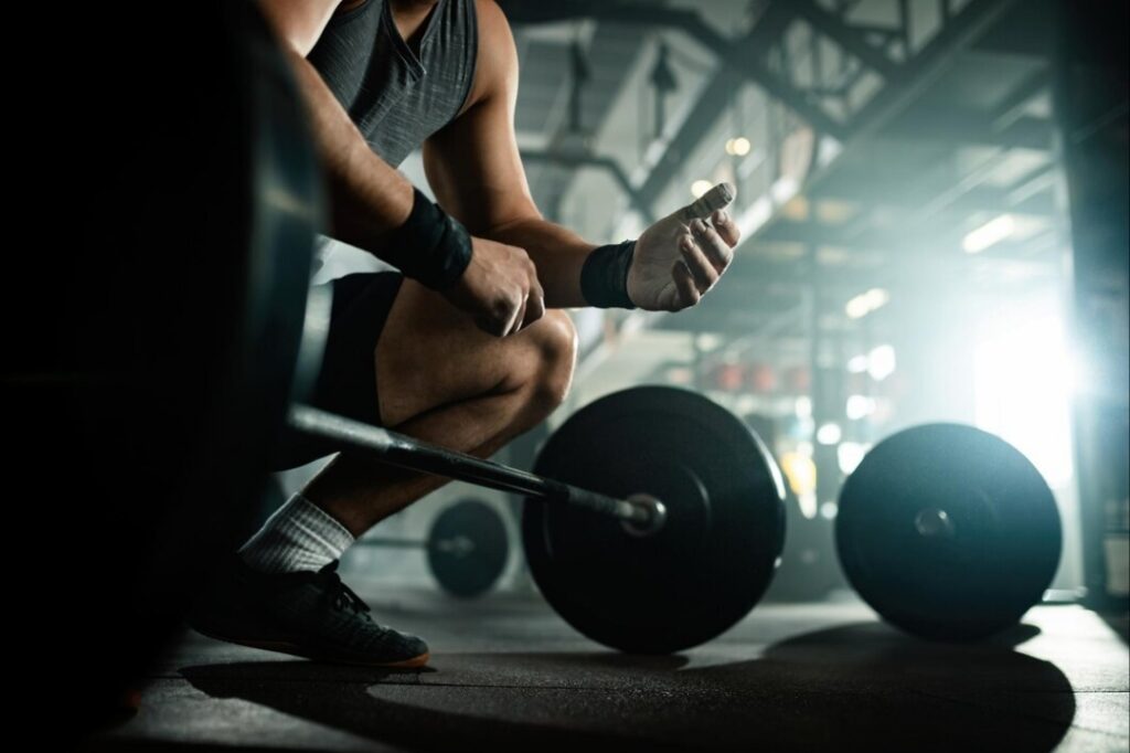Man-kneeling-near-barbell-in-gym