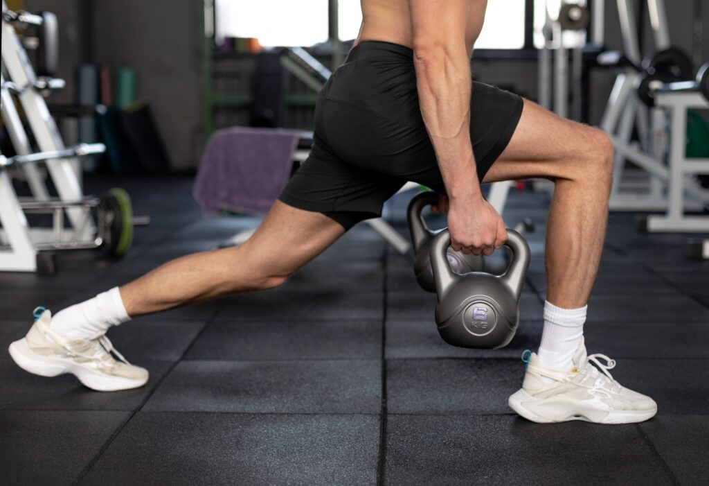 Man-lunging-with-gray-kettlebell-on-gym-floor-strength-training
