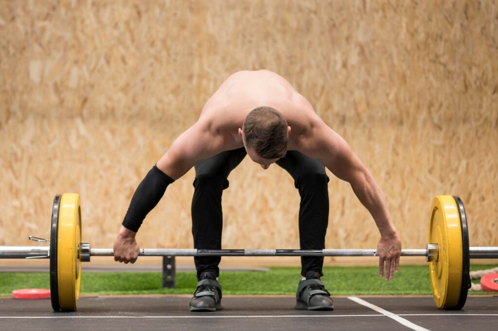 Man-preparing-for-a-barbell-deadlift-with-a-wide-grip-in-a-gym-setting
