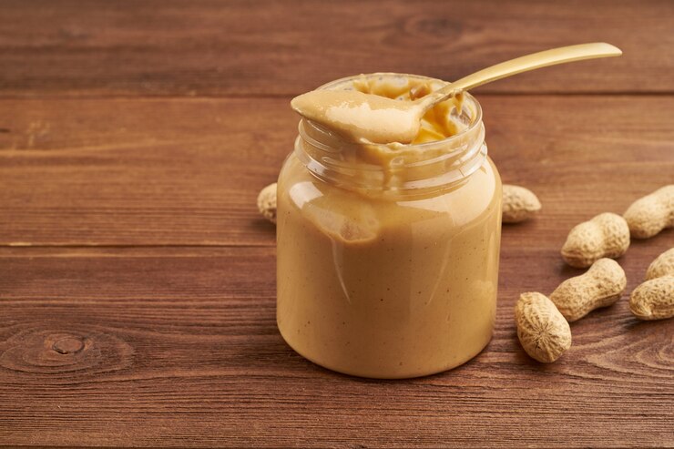 Peanut–butter–jar–with–spoon–on–wooden–table