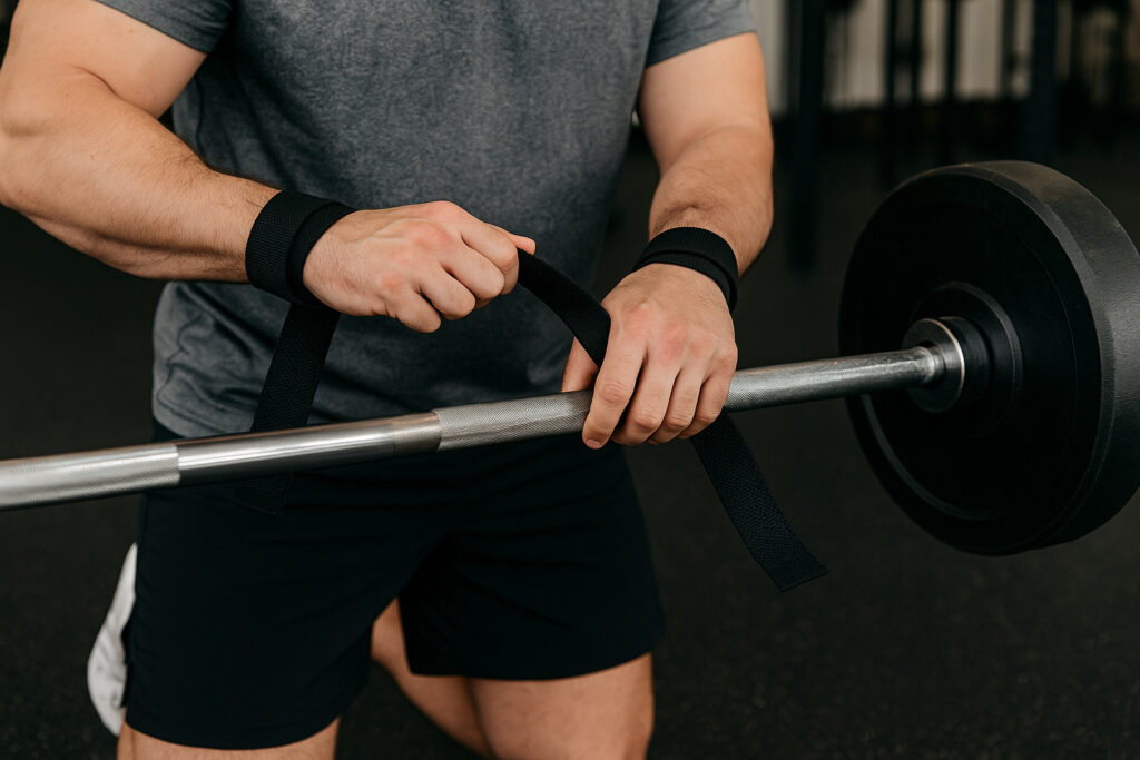 Man-using-lifting-straps-on-barbell-for-weightlifting-in-gym